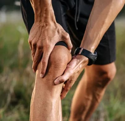 Person holding painful knee outdoors, illustrating injury possibly treated with Arthroscopy in India.