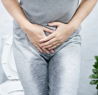 Person with urinary discomfort near toilet, illustrating condition treated by Bladder Suspension Surgery in India.