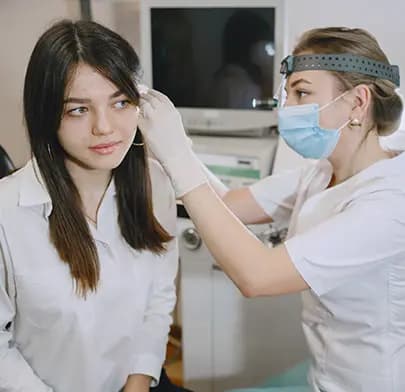 Doctor examines patient's ear for infection in ENT clinic.