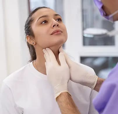 Doctor palpates patient's neck during thyroidectomy evaluation
